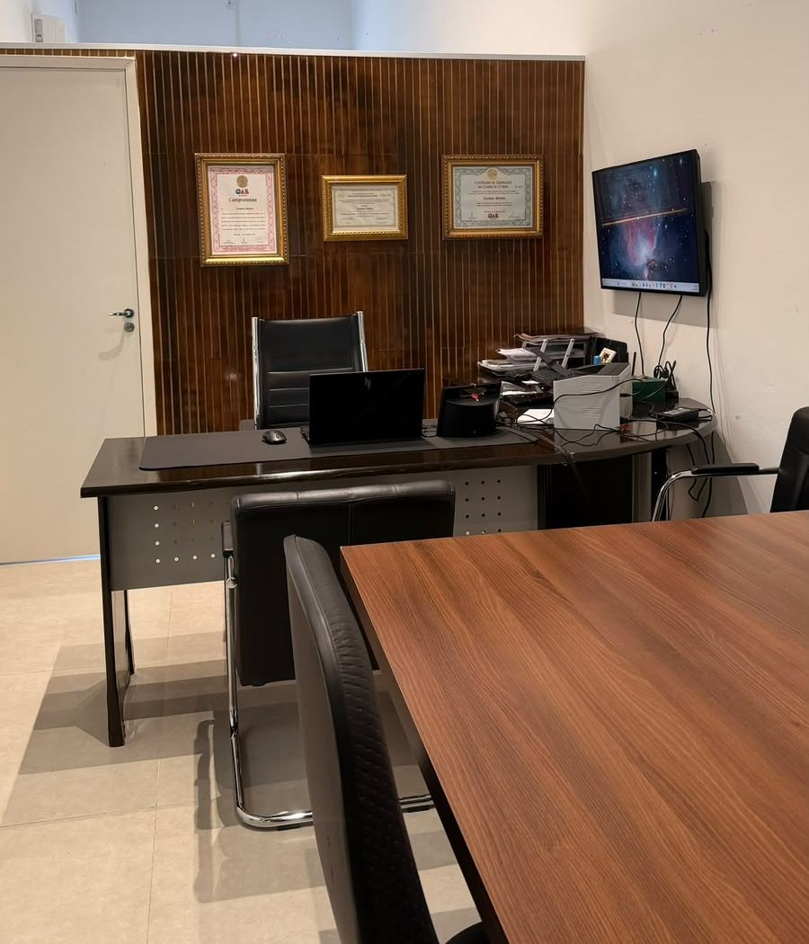 Sala de atendimento com mesa do advogado e certificados na parede